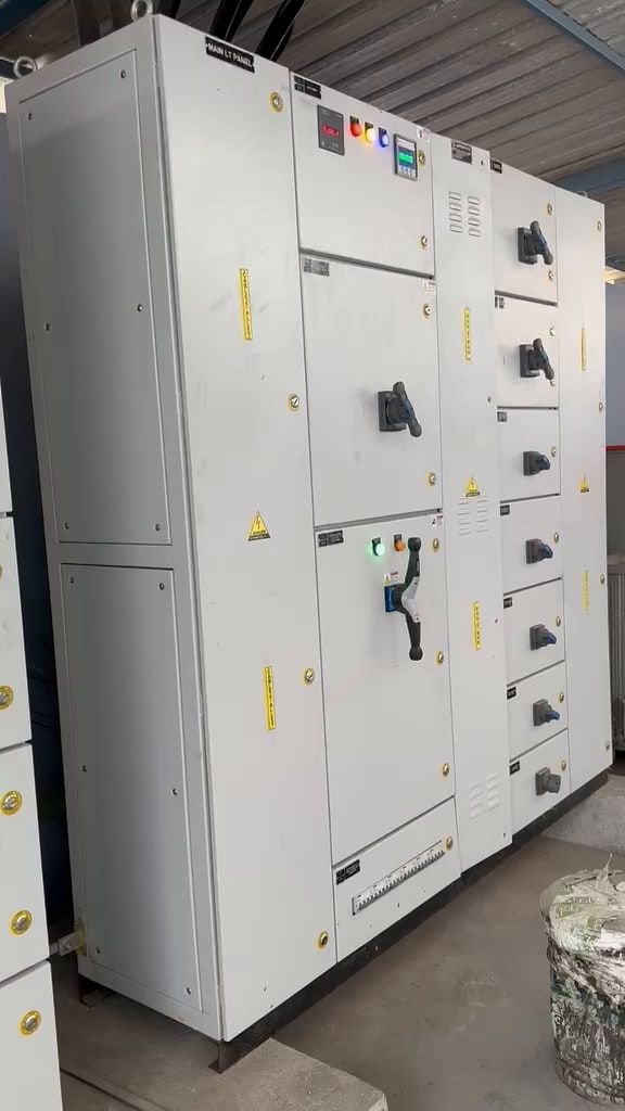 A large multi-section LT panel lineup standing on a concrete plinth under a shed roof, doors closed, with metering and indication across the upper fascia and rotary selectors below.
