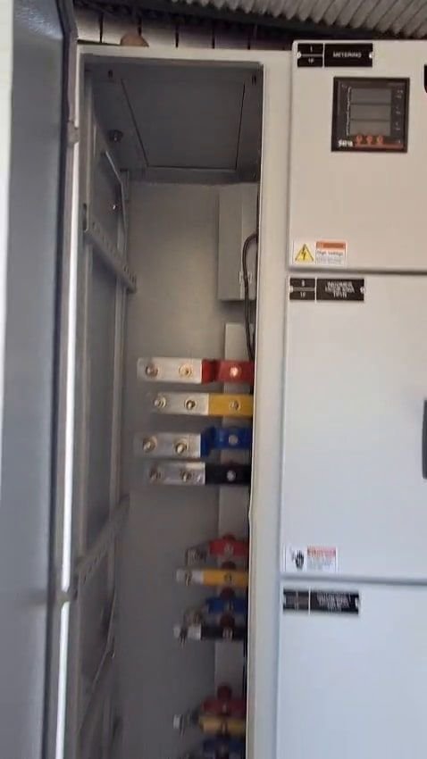 Front elevation of a finished LT panel, doors closed, with a metering window at the top, three indicator lamps and a column of rotary selector switches down the compartment doors.