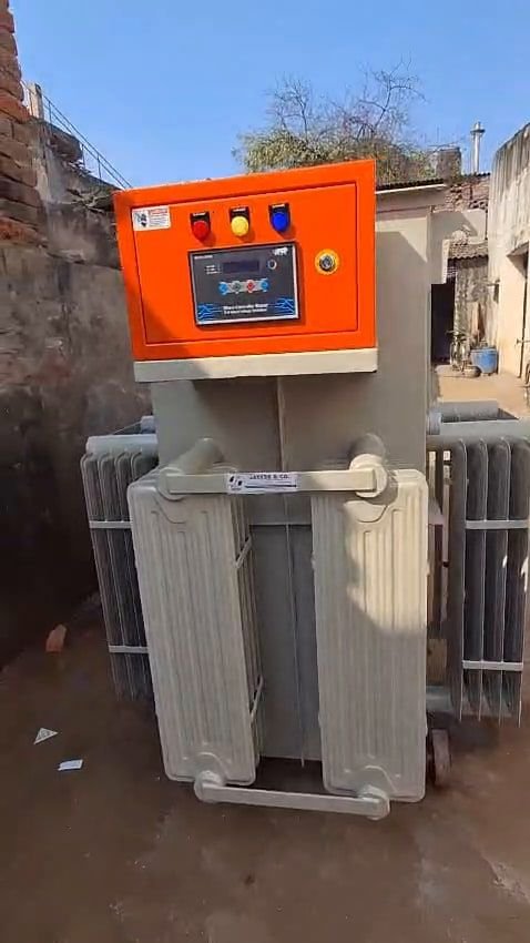 A transformer tank with pressed-steel radiator banks on both sides, lifting lugs at the corners, and an orange-fronted control box mounted on top carrying indicator lamps and a display. A Jayess & Co. label is fixed to the tank.